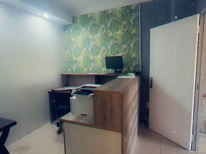 A compact office space featuring a built-in reception desk, tiled flooring, and a decorative feature wall.