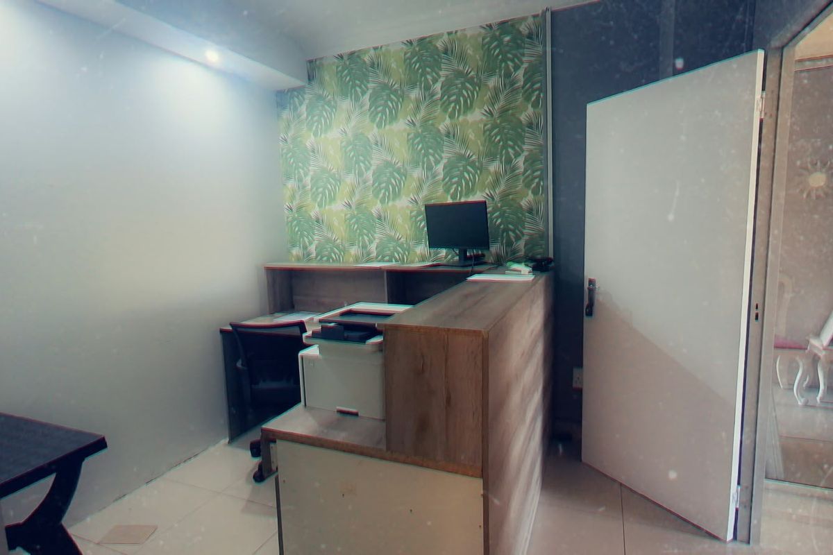 A compact office space featuring a built-in reception desk, tiled flooring, and a decorative feature wall.