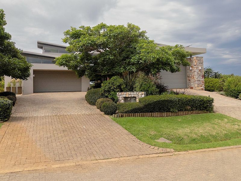 Modern residential property featuring a double garage, stone-clad accents, and a paved driveway with established landscaping.