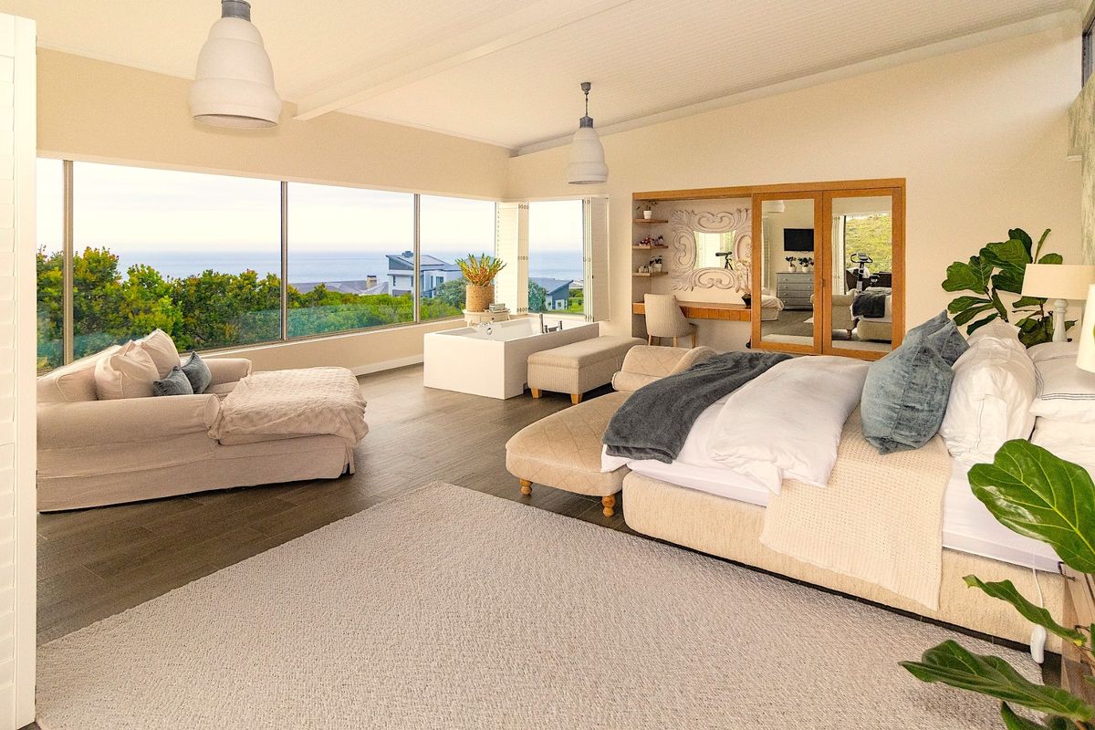 Spacious master bedroom featuring floor-to-ceiling windows with ocean views, a built-in bathtub, and a custom vanity area with high-quality finishes.