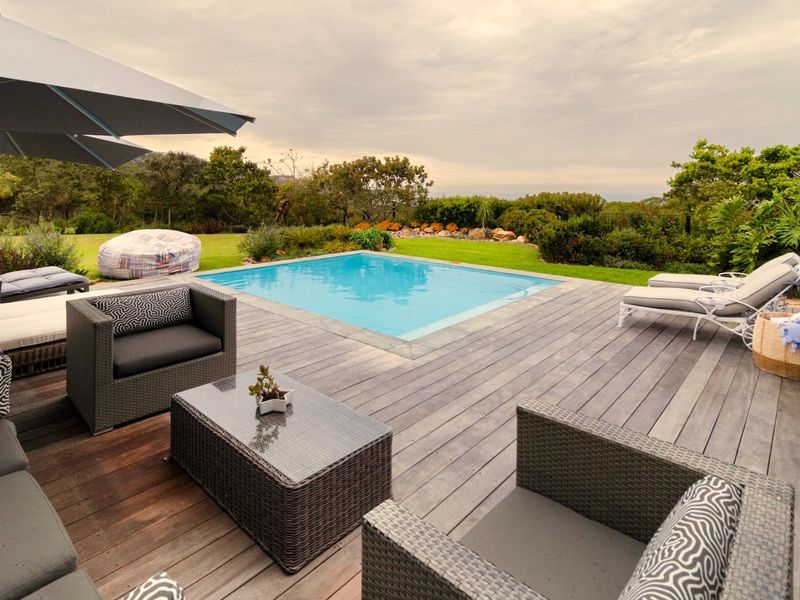 Outdoor entertainment area featuring a swimming pool set within timber decking, surrounded by a well-maintained landscaped garden.