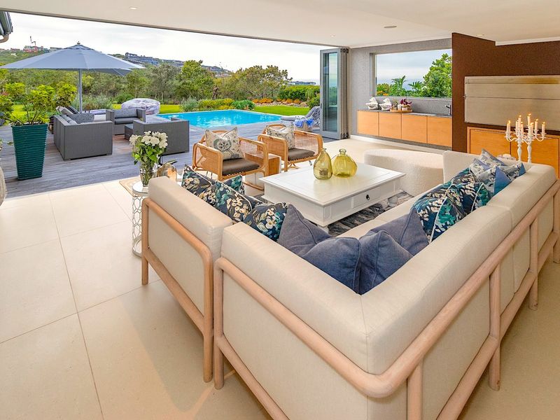 Spacious open-plan living area featuring seamless indoor-outdoor flow through large bi-fold doors to a deck and pool area.