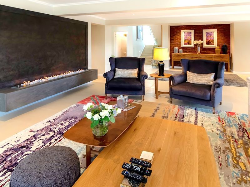Spacious living room featuring a modern built-in fireplace, elegant tiled flooring, and a striking exposed brick feature wall.