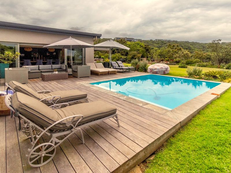 Outdoor entertainment area featuring a swimming pool, extensive timber decking, and seamless access to the main living space through large sliding glass doors.