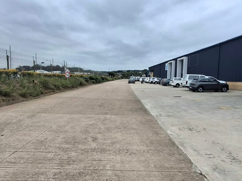 Industrial property exterior featuring a large concrete driveway, metal cladding facade, and secure perimeter electric fencing.