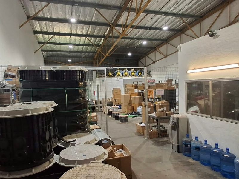Spacious industrial warehouse unit featuring high ceilings with exposed steel trusses, concrete flooring, and secure wire mesh partitioning for storage or operational use.