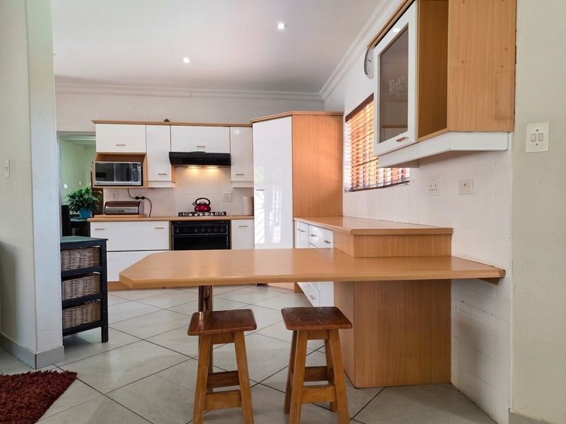 A functional kitchen featuring light wood and white cabinetry, a built-in breakfast nook, gas stove, and tiled flooring with recessed lighting.