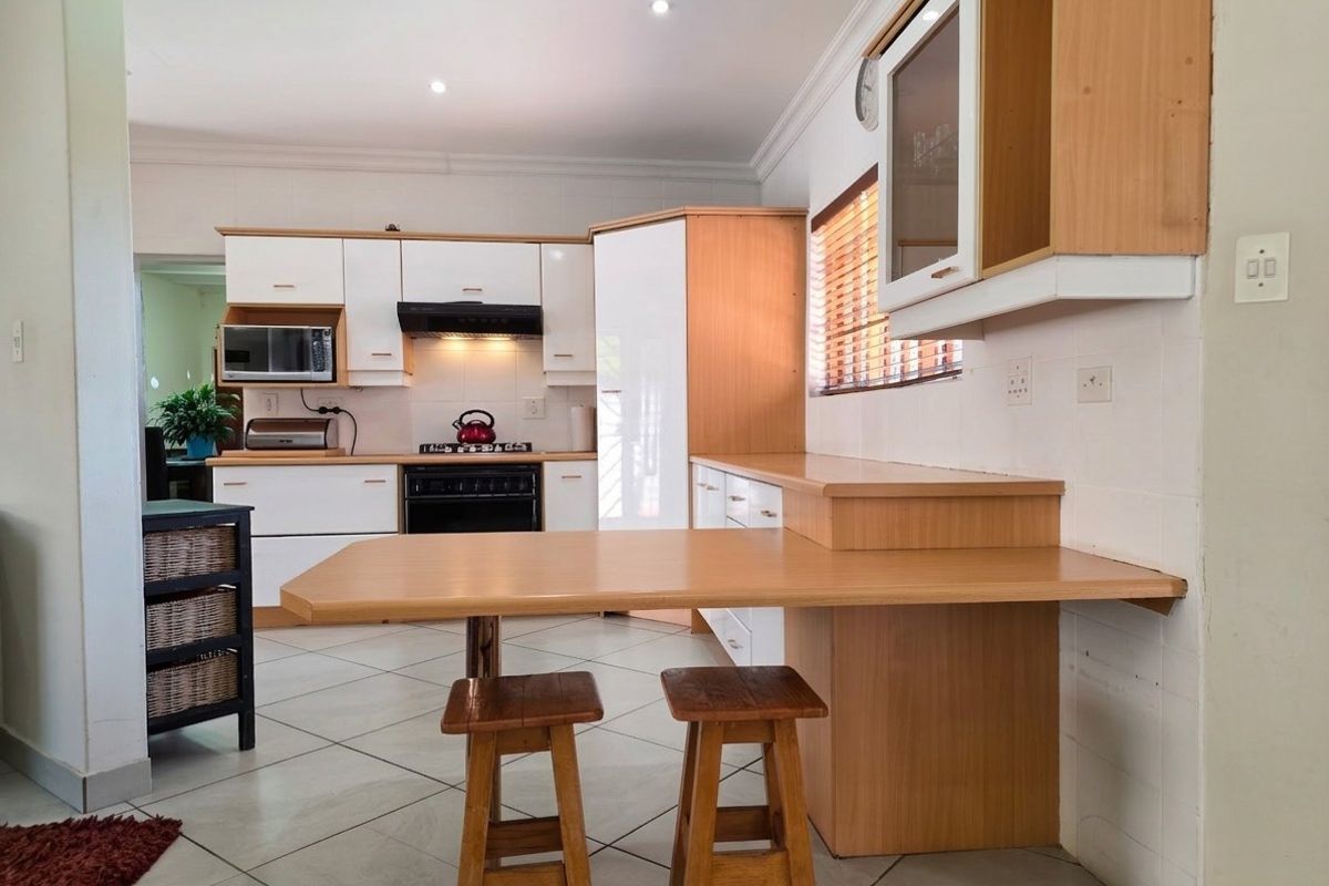 A functional kitchen featuring light wood and white cabinetry, a built-in breakfast nook, gas stove, and tiled flooring with recessed lighting.