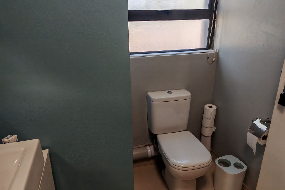 A functional bathroom featuring a standard toilet, vanity basin, and a window for natural light.