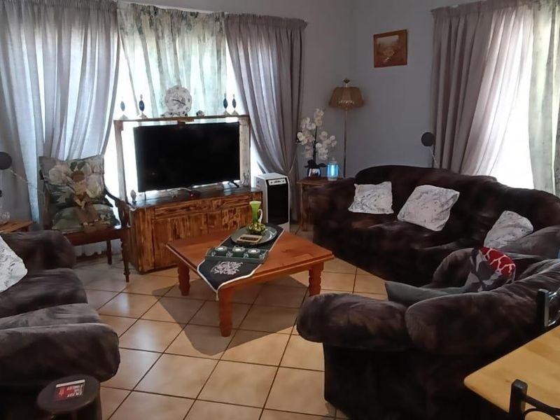A comfortable living room featuring ceramic floor tiles and large windows with curtain tracks, providing a functional and lived-in space.