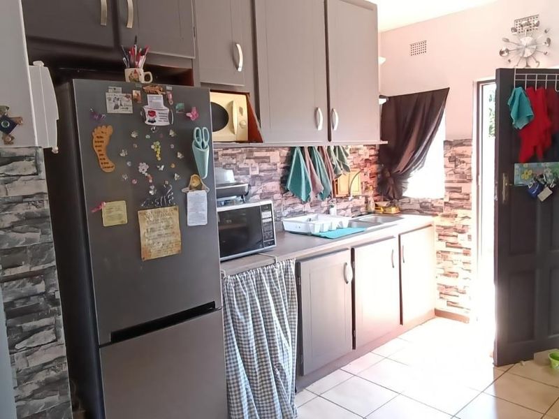 A functional kitchen featuring built-in cabinetry, tiled flooring, and decorative stone-look wall finishes with direct access to the exterior.