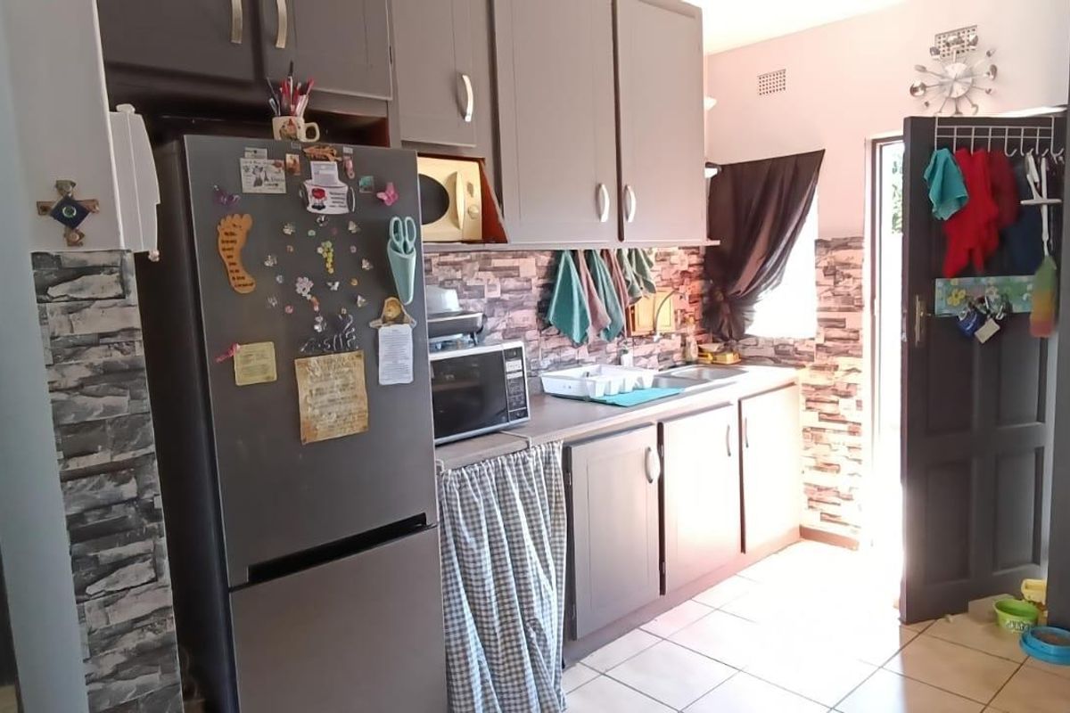 A functional kitchen featuring built-in cabinetry, tiled flooring, and decorative stone-look wall finishes with direct access to the exterior.