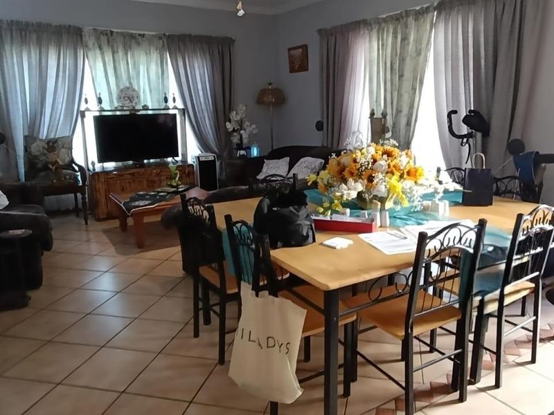 An open-plan living and dining area featuring tiled flooring and access to the outdoors through sliding glass doors.