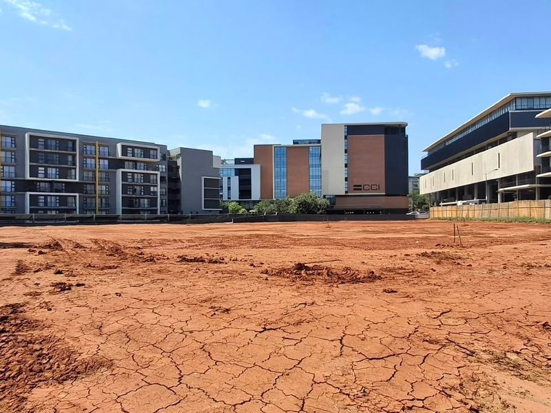 A vacant commercial land plot featuring cleared, level ground situated in a developed urban area with surrounding multi-story commercial buildings.