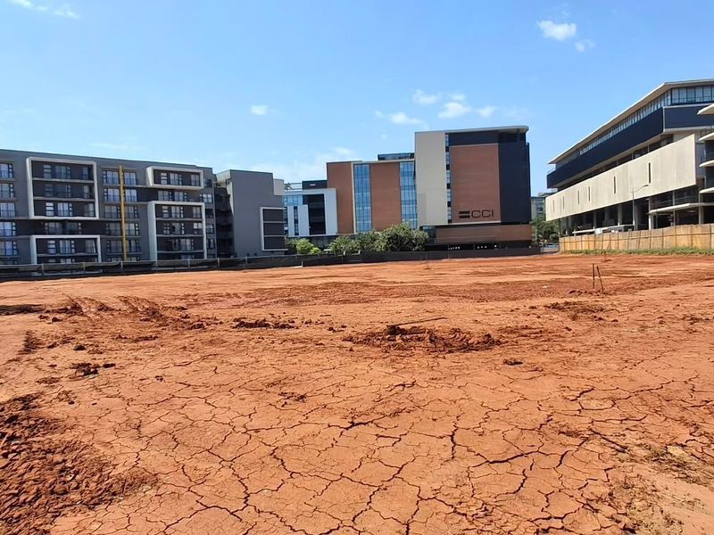 A vacant commercial land plot ready for development, situated in a prime location surrounded by modern multi-story commercial and residential buildings.