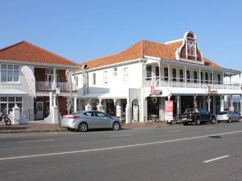 A street-level view of a commercial office building featuring traditional architecture, terracotta roof tiles, and a prominent balcony and veranda.