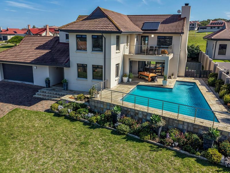 Aerial view of a modern double-story house featuring a swimming pool, paved patio, balcony, and well-maintained garden.
