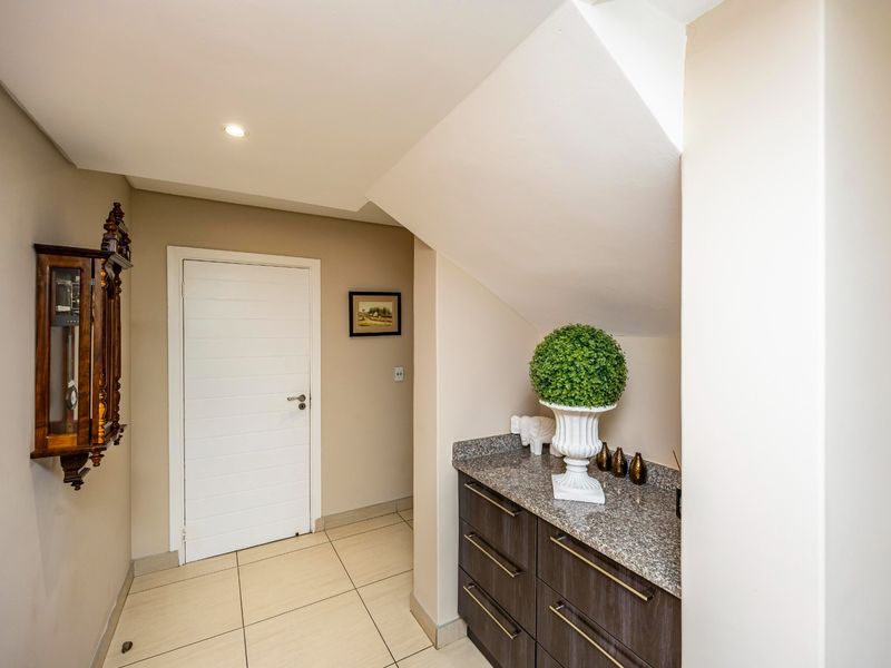 A well-maintained hallway featuring built-in cabinetry with granite countertops, tiled flooring, and recessed lighting, providing a clean and functional transition space.