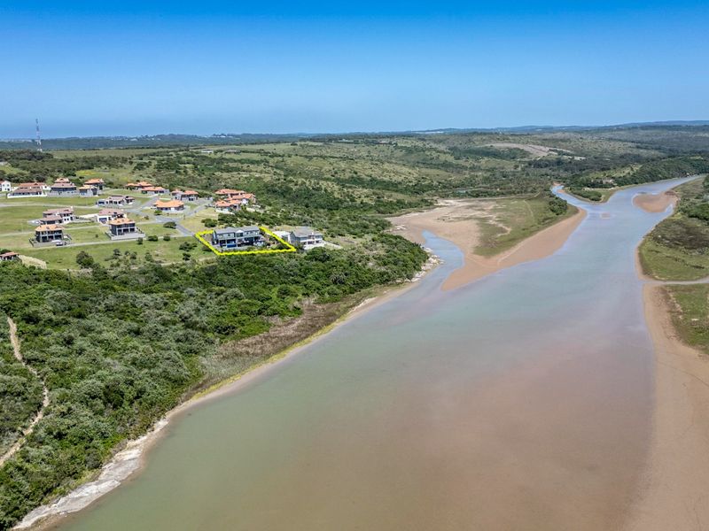 Aerial view of a residential property situated within a coastal estate, overlooking a river estuary and natural landscape.