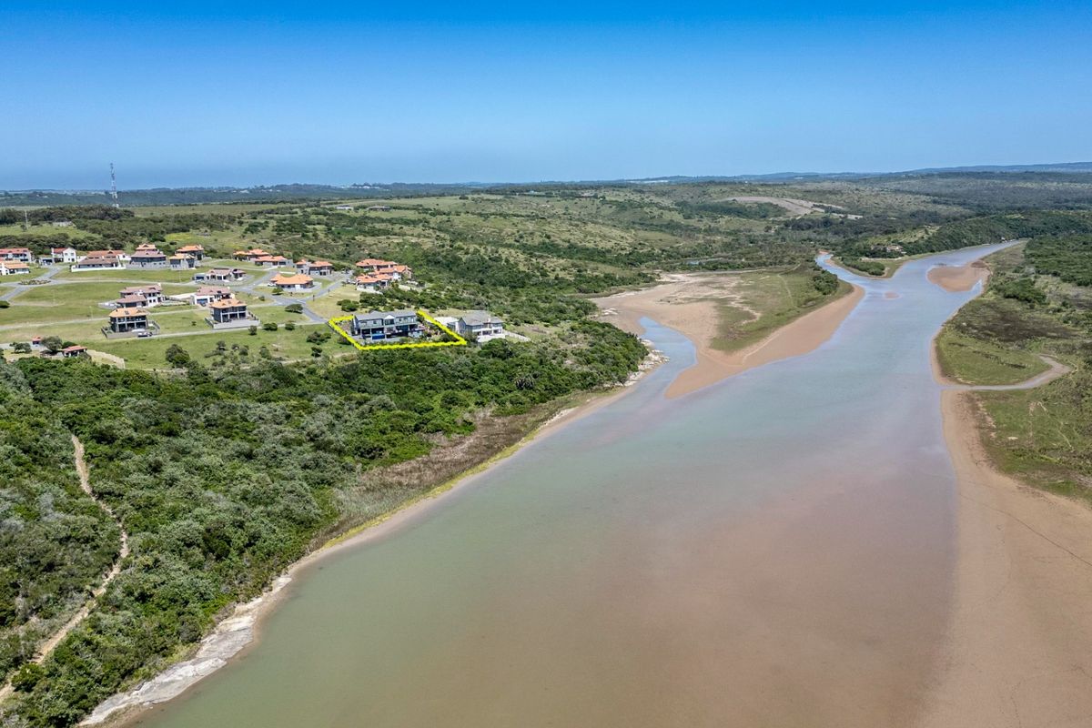 Aerial view of a residential property situated within a coastal estate, overlooking a river estuary and natural landscape.