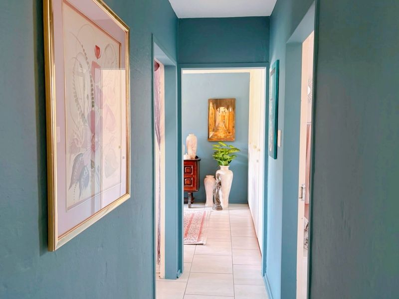 A bright hallway featuring tiled flooring and built-in storage cupboards, connecting various rooms within the townhouse.