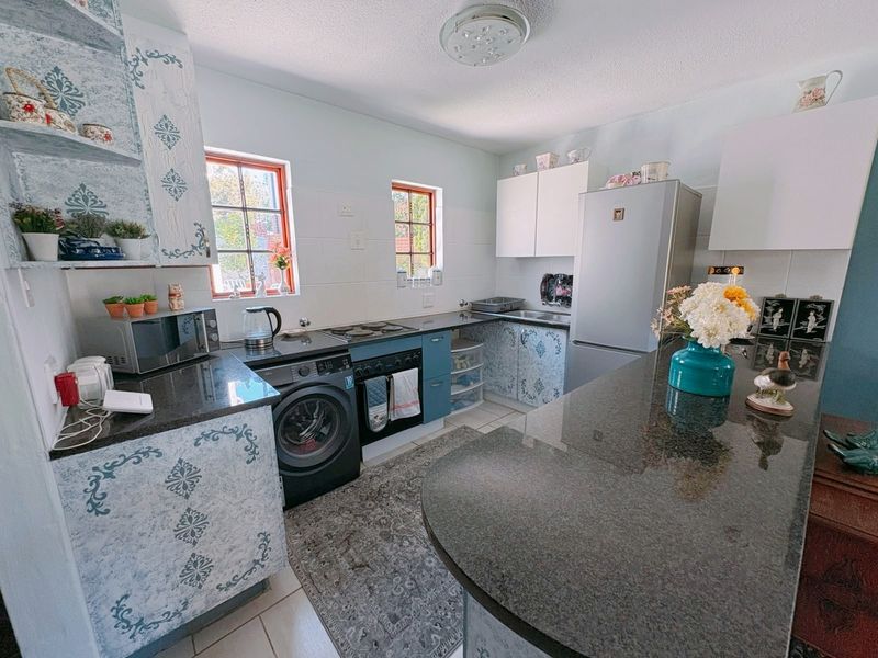A functional kitchen featuring granite countertops, built-in cabinetry, an electric hob, and an integrated oven, offering a practical layout for daily meal preparation.