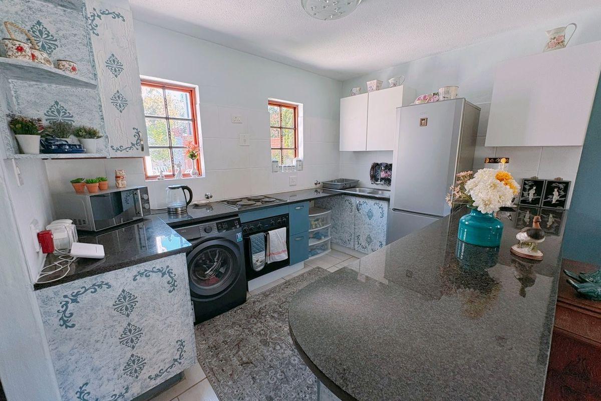 A functional kitchen featuring granite countertops, built-in cabinetry, an electric hob, and an integrated oven, offering a practical layout for daily meal preparation.