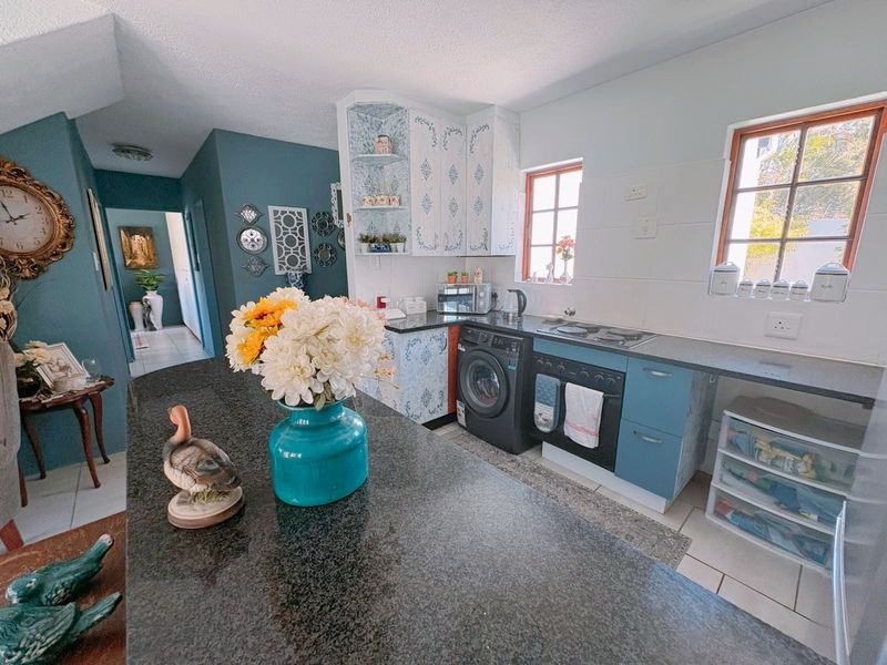 A functional kitchen featuring granite countertops, built-in cabinetry, an integrated oven and hob, and a dedicated space for a washing machine.