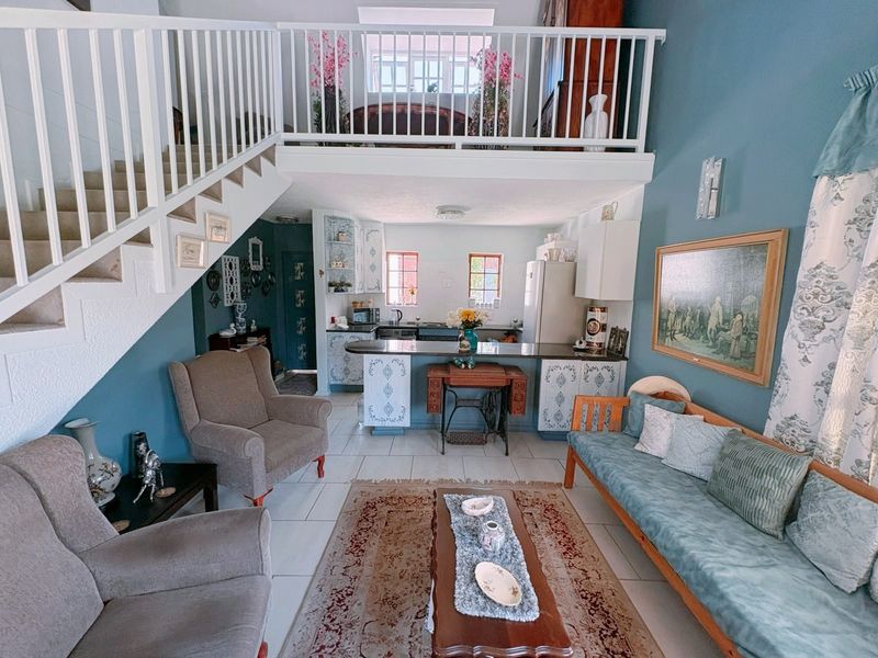 Open plan living area featuring a kitchen with island, tiled flooring, and a staircase leading to a mezzanine level.