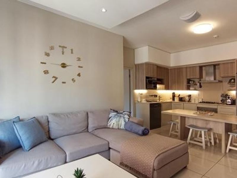 Modern open-plan living area featuring a well-appointed kitchen with built-in cabinetry, integrated appliances, and sleek tiled flooring throughout the space.