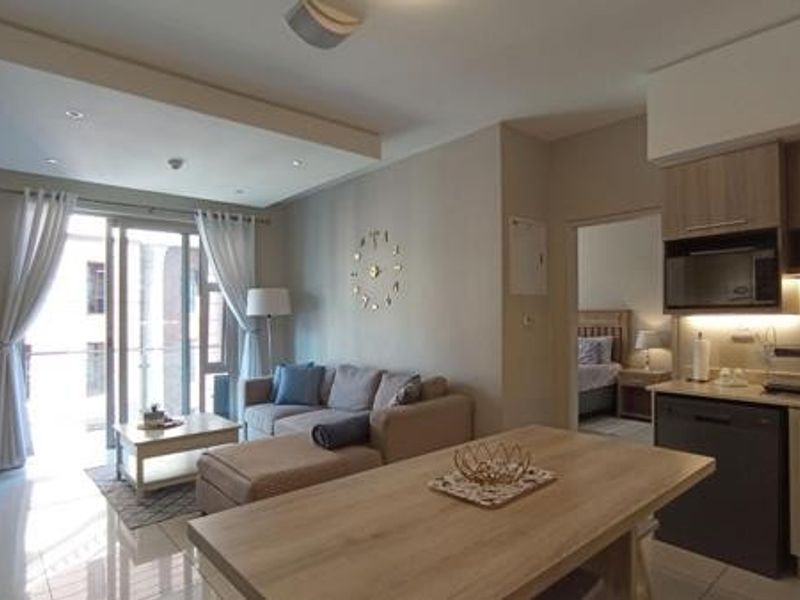Modern open-plan living area featuring a contemporary kitchen with built-in appliances, tiled flooring, and seamless access to a private balcony.