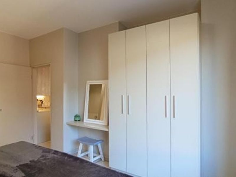 A bedroom featuring a large white built-in wardrobe and a convenient built-in vanity shelf, offering practical storage and dressing space.