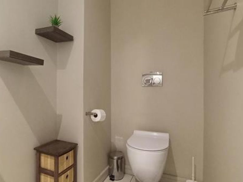 A modern bathroom featuring a wall-hung toilet with a concealed cistern, a wall-mounted basin, and a towel rail.