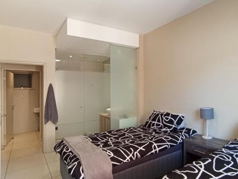 Bedroom featuring tiled flooring and an integrated en-suite bathroom separated by a modern frosted glass partition.