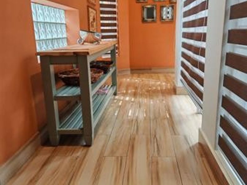 A bright hallway featuring wood-look tile flooring, glass block windows, and modern zebra blinds, creating a warm and inviting transition space.