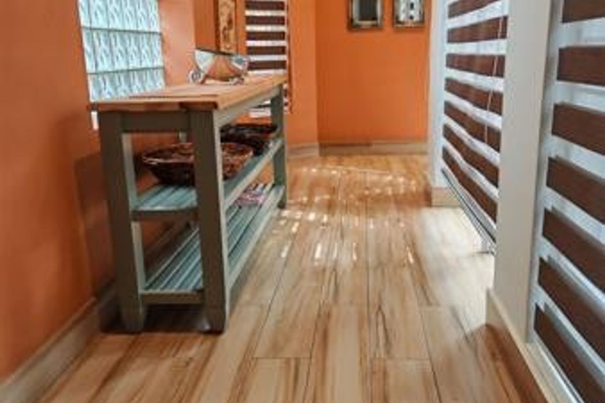 A bright hallway featuring wood-look tile flooring, glass block windows, and modern zebra blinds, creating a warm and inviting transition space.