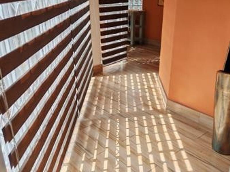 A bright hallway featuring modern tiled flooring, zebra blinds, and decorative glass block windows, creating a clean and well-lit transition space.