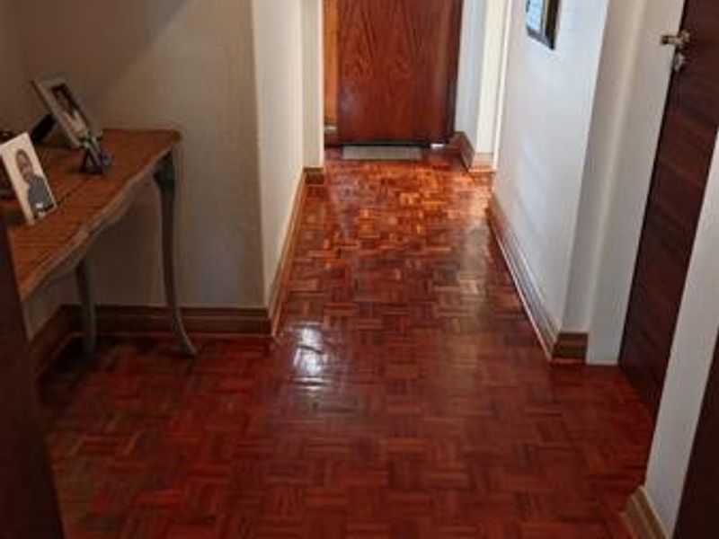 A well-maintained hallway featuring polished parquet flooring and classic wooden doors, providing a warm and inviting entrance to the home.