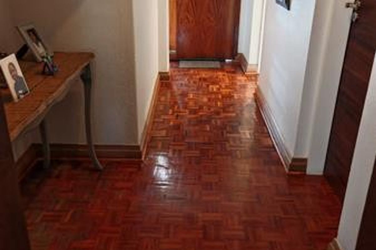 A well-maintained hallway featuring polished parquet flooring and classic wooden doors, providing a warm and inviting entrance to the home.