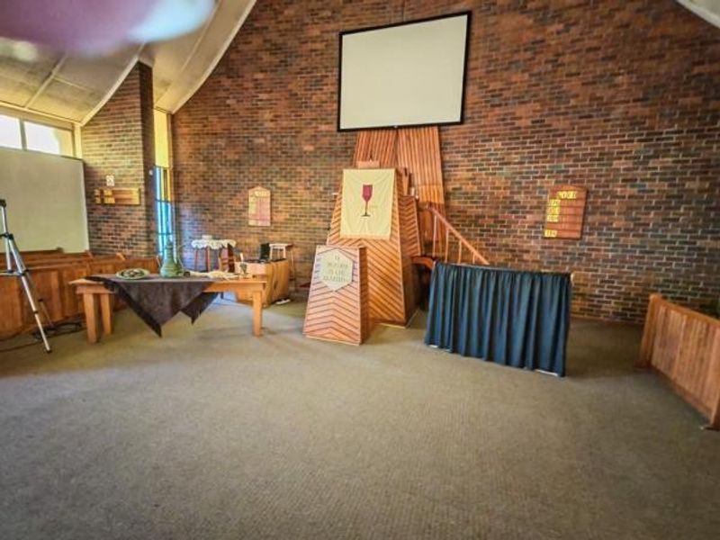 Interior view of a hall featuring exposed brick walls, a vaulted ceiling, and a built-in wooden pulpit area.