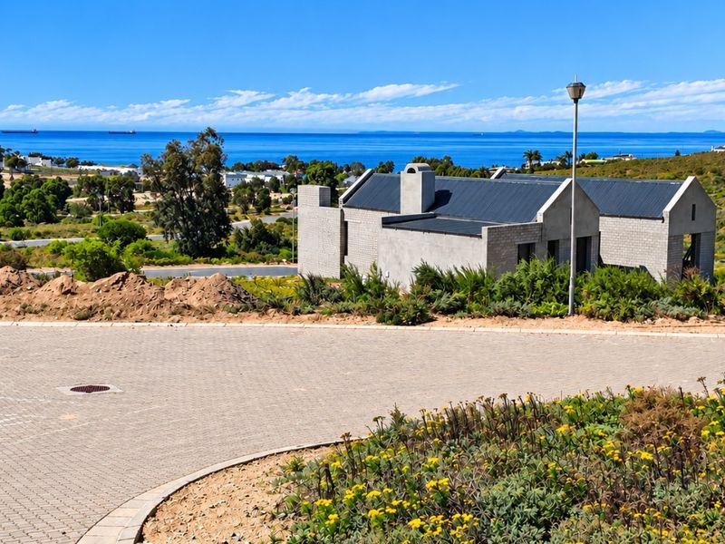 A view of a modern residential property with a paved driveway and scenic ocean views in a quiet coastal estate setting.