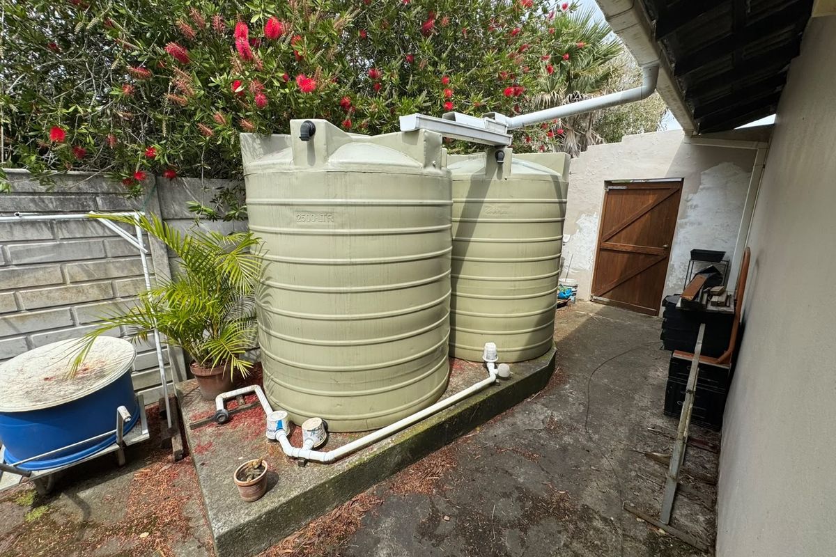 Rear exterior area featuring two large water storage tanks on a concrete plinth, connected to the roof guttering system.