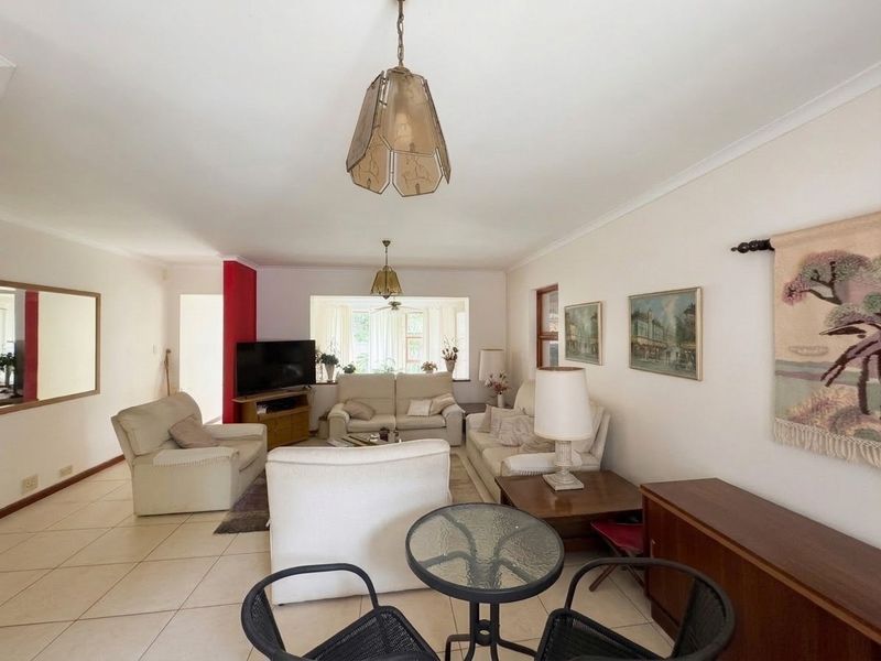 Spacious living room featuring neutral tiled flooring, coved ceilings, and ample natural light, offering a comfortable and versatile area for relaxation.