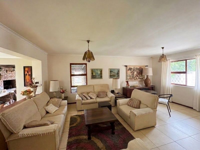 A spacious living room featuring neutral tiled flooring, coved ceilings, and leaded glass windows, offering a bright and comfortable living space.
