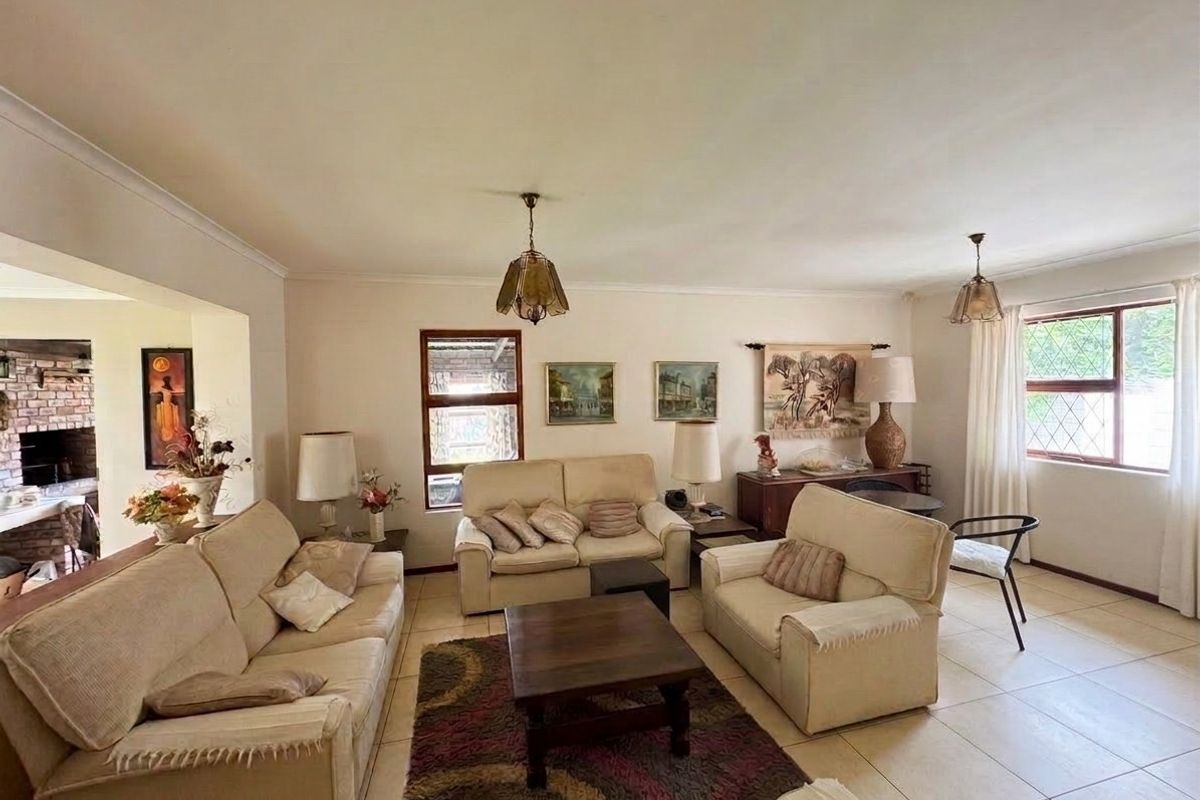 A spacious living room featuring neutral tiled flooring, coved ceilings, and leaded glass windows, offering a bright and comfortable living space.