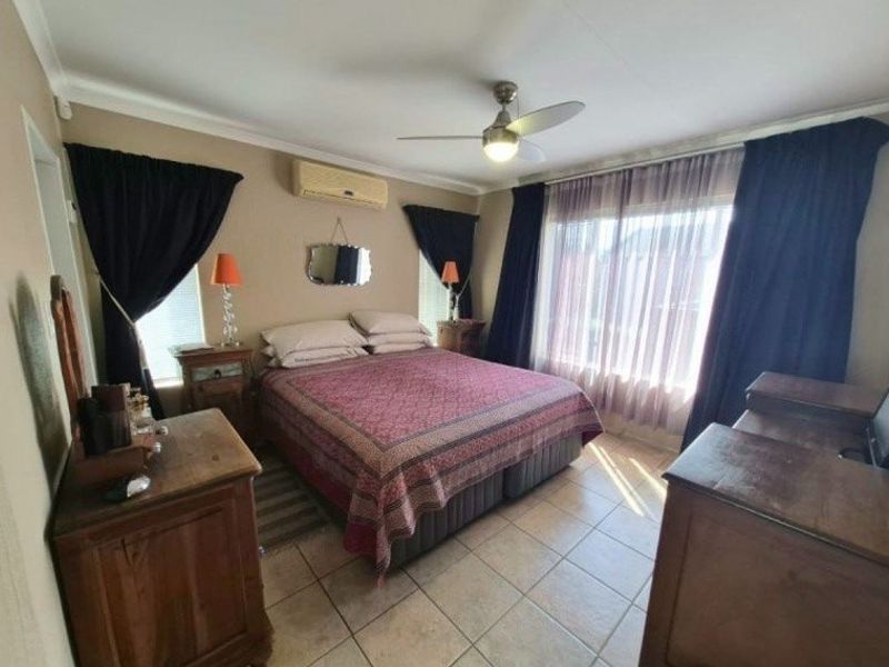 A bedroom featuring tiled flooring, a ceiling fan, and a wall-mounted air conditioning unit.