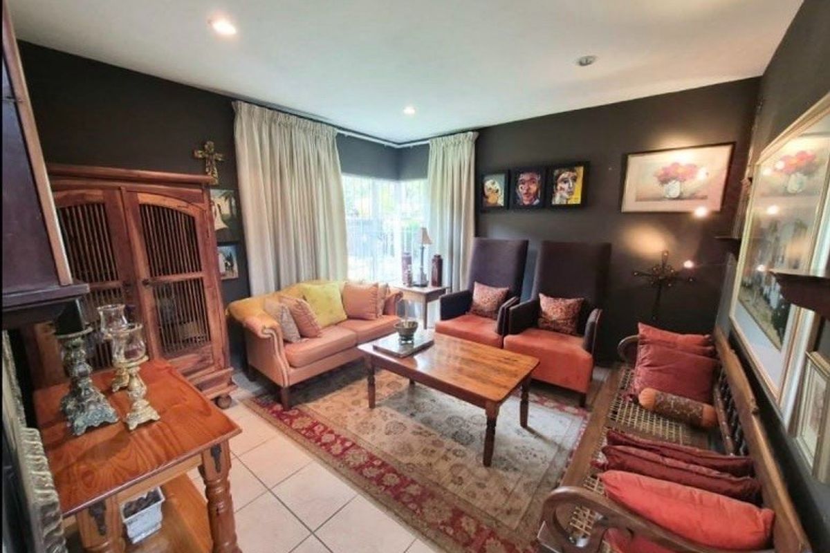 A cozy living room featuring dark painted walls, tiled flooring, and recessed downlighting, creating a warm and intimate atmosphere.