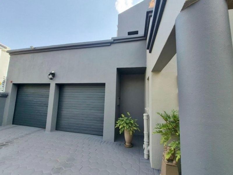Front elevation of the property featuring a double garage with roller doors and a paved driveway area.