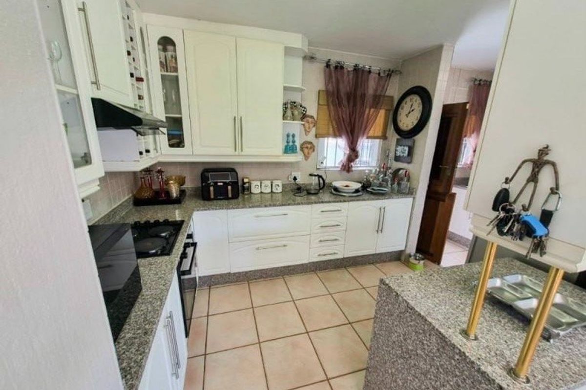 A functional kitchen featuring granite countertops, white cabinetry, and tiled flooring, offering a practical layout with integrated cooking appliances.