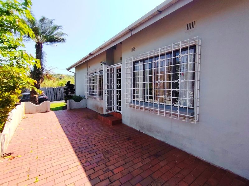 Rear exterior view of the townhouse featuring a brick paved patio area, security bars on windows, and a security gate.